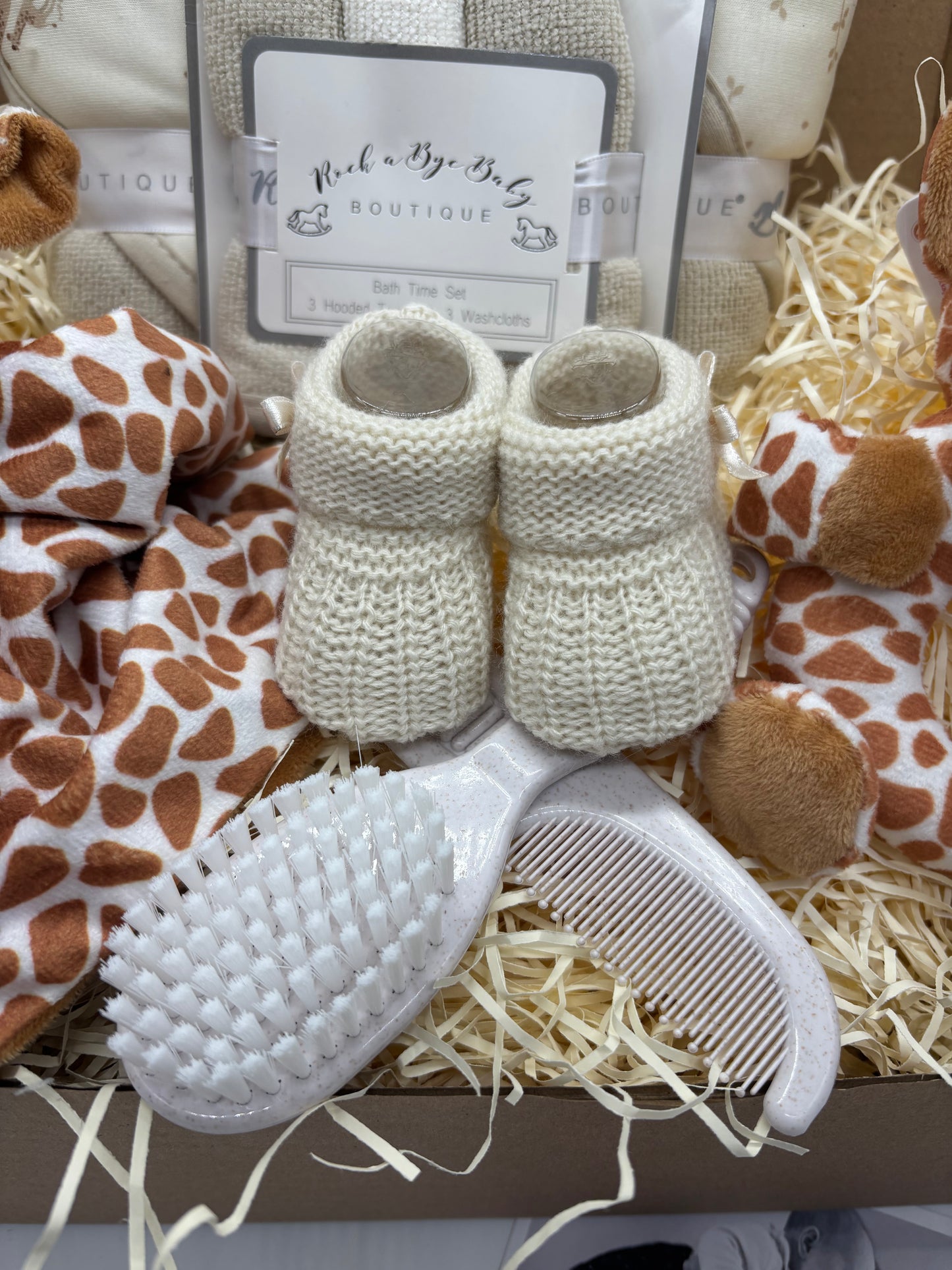 Cream knitted baby booties with a baby hairbrush and comb set