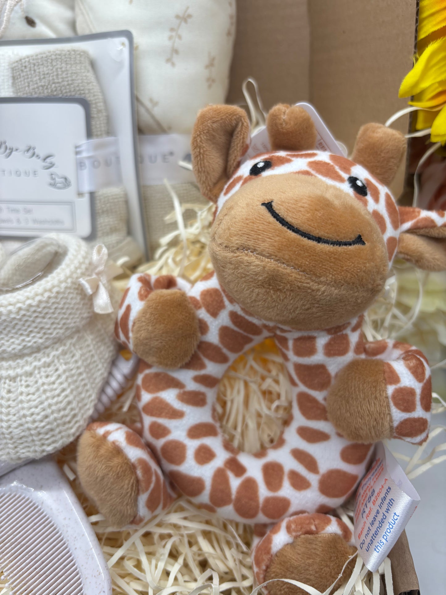 Plush giraffe baby rattle with ring-shaped body in the giraffe gift box