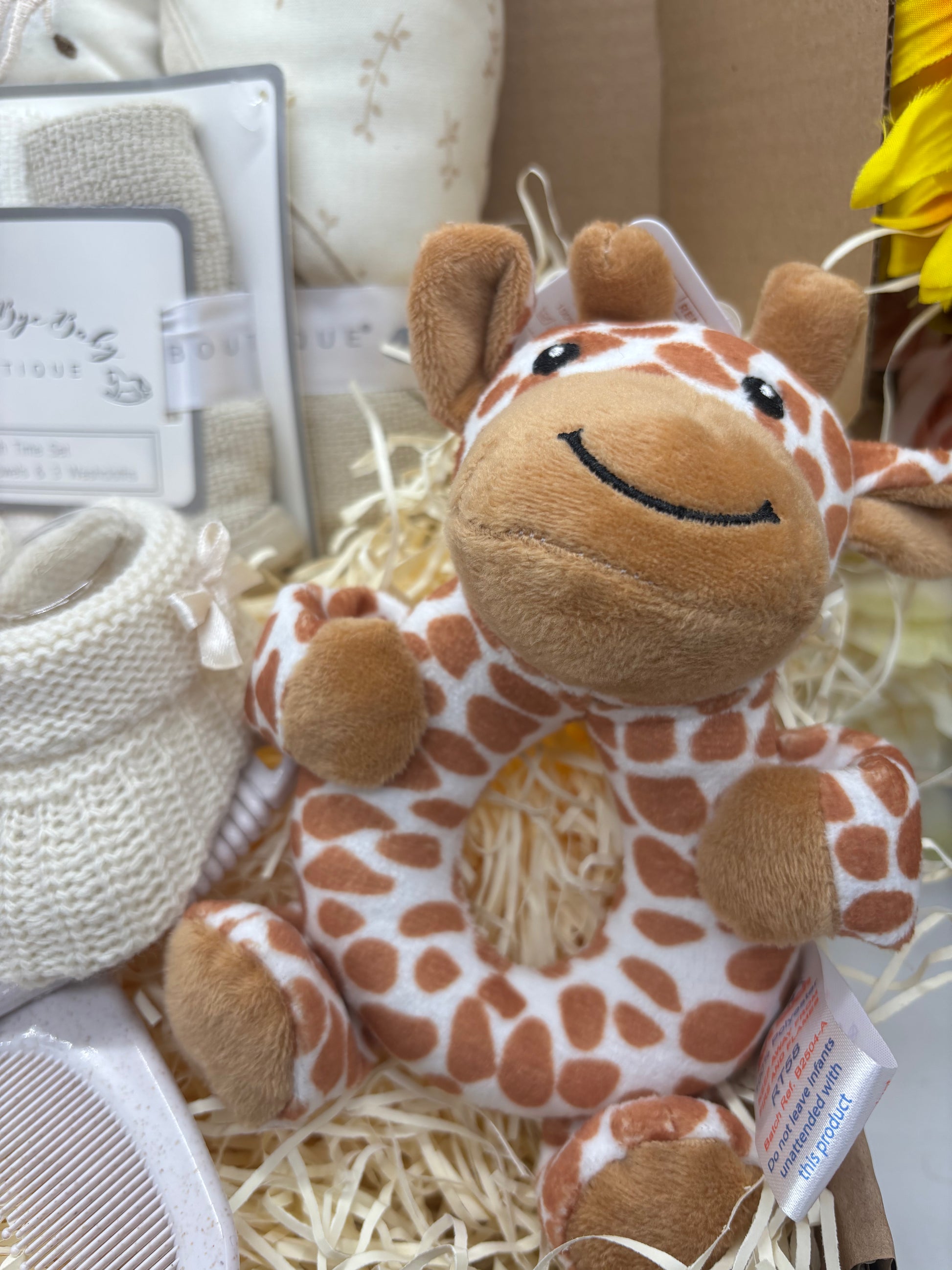 Plush giraffe baby rattle with ring-shaped body in the giraffe gift box